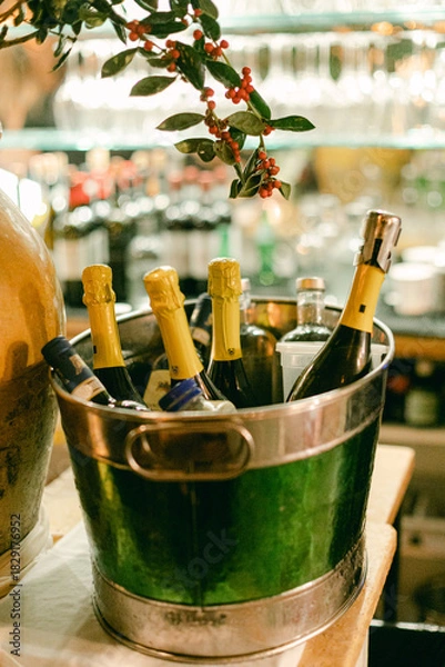 Fototapeta Festive gathering at a bar featuring chilled champagne bottles in an ice bucket with decorative greenery