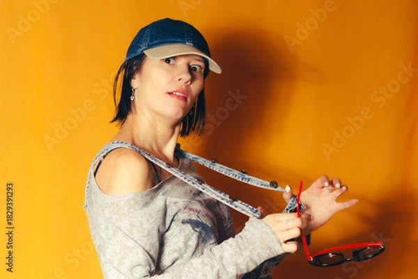Obraz Surprised woman posing with suspenders on orange background