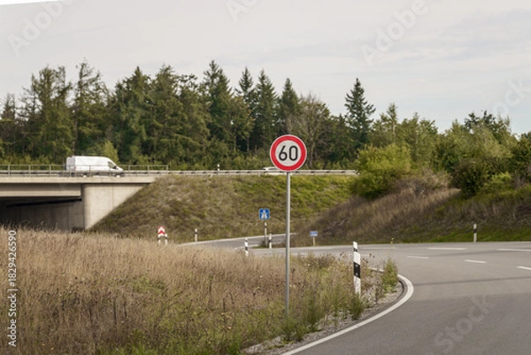 Fototapeta Crossing in the countryside sunlight near a bridge with a speed limit sign