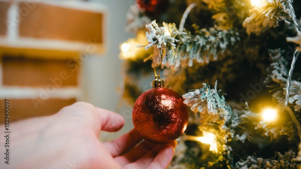Obraz Hand caressing a red Christmas ball on a tree