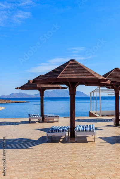 Obraz Sun umbrellas and chaise lounges on tropical beach. Concept of rest, relaxation, holidays, resort