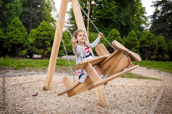 Obraz Cute little girl on a swing. Smiling child playing outdoors in summer.
