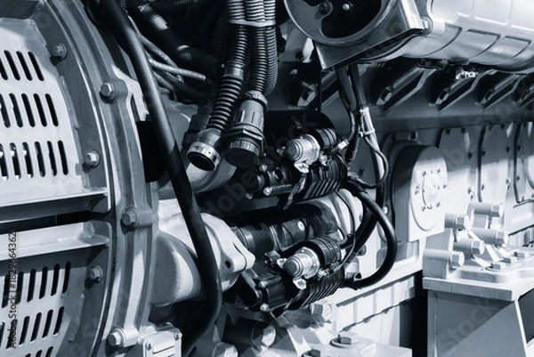 Obraz large blue diesel engine generator with  black hose attached to it. hose connected to engine and positioned in center. engine is powerful device, likely used for industrial purposes