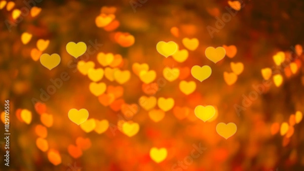 Fototapeta Abstract beautiful blurred gold-yellow orange and red colored of heart bokeh like autumn leaves from ornamental lights flickering in the park. Background for Autumn season, Valentine or Love concept.