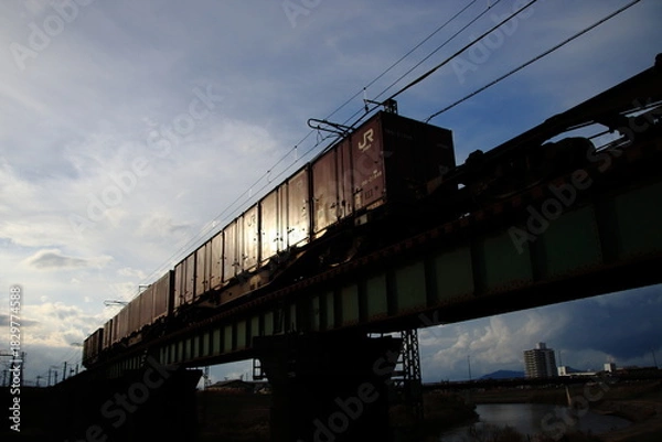 Obraz 夕日を反射して疾走するコンテナ貨物列車のイメージ