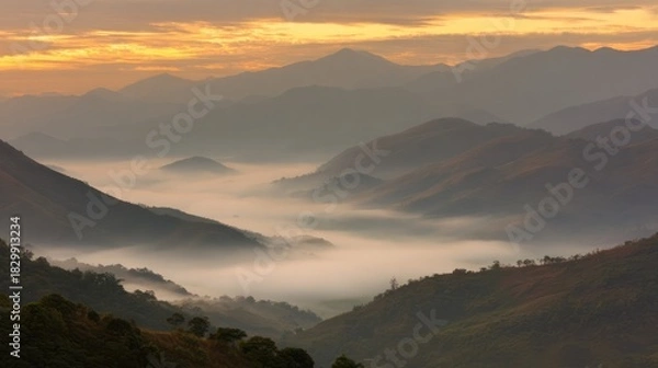 Obraz At dawn, the mountain landscape shrouded in mist shines with golden light on the panoramic foothills. Travel magazine, destination brand, designed specifically for outdoor magazines and nature guides.