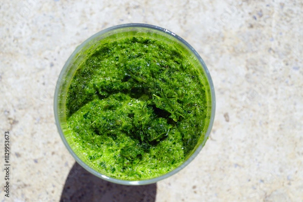 Fototapeta Top view of green herb smoothie showing creamy texture with visible leafy green specks. Illustrates blended vegetable drink, healthy beverage choice, fresh greens consumption, and celery use.