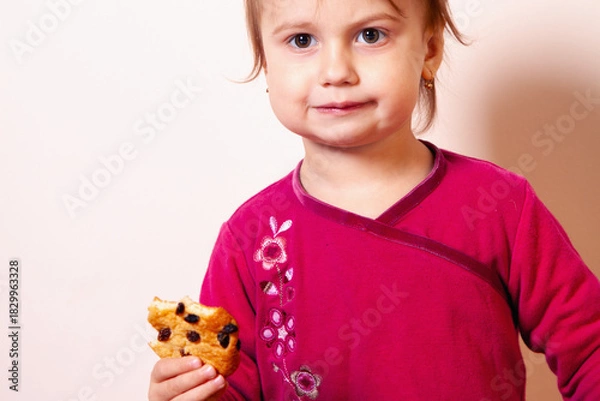 Fototapeta Girl with a calm expression holding a bitten treat. Copy space.
