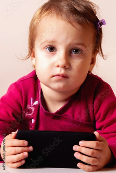 Fototapeta Child looking happy while using a touchscreen device.