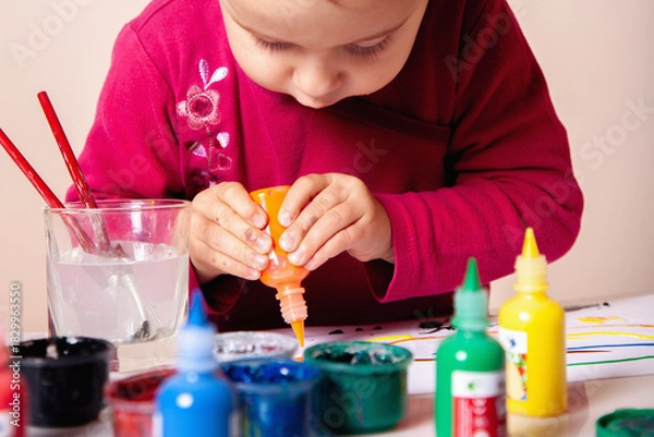 Fototapeta Small child deeply focused on her artistic project.
