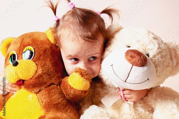 Fototapeta Child hugging two large teddy bears with a warm smile.