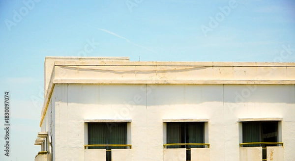 Fototapeta Front view of a tall hotel building with a bright blue cloudy sky in the background. Window hotel with vintage design in center of the town. Hotel at the city metropolitan concept