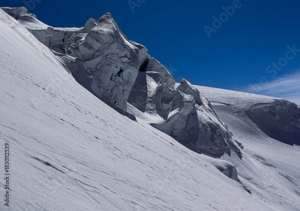 Fototapeta Dramatic icy rock formations and a steep snowy slope on a high-altitude glacier in the swiss Alps under a deep blue sky. A striking winter landscape with rugged natural textures.