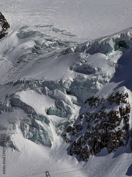 Obraz Snowy glacier landscape with dramatic rocky ridges in the Swiss Alps near Zermatt. Winter mountain scenery captured in bright sunlight