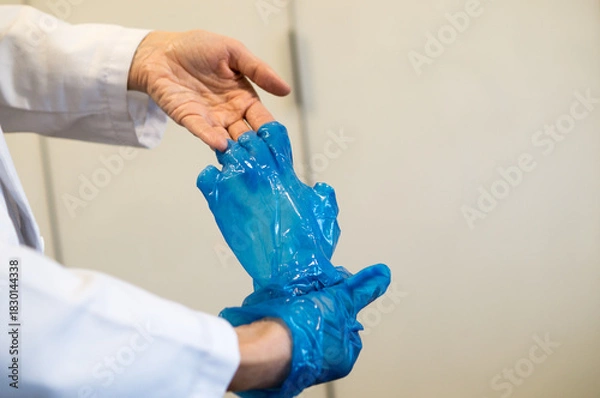 Obraz Doctor or Nurse Rolling Off Blue Barrier Glove, Focusing on Hand Hygiene Procedure.