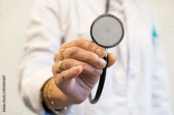 Obraz Close-up of Doctor's Hand Extending Stethoscope with Rings and Bracelets, Unsafe Medical Environment.