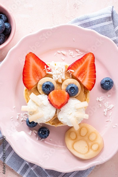 Fototapeta Creative breakfast idea featuring a cat face made from fruit and pancakes on a pink plate