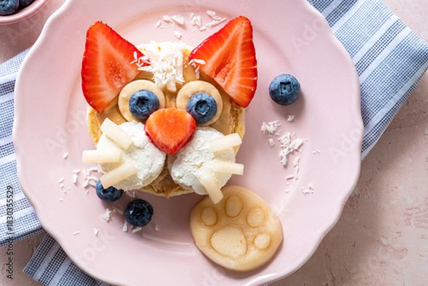 Fototapeta Creative breakfast idea featuring a cat face made from fruit and pancakes on a pink plate