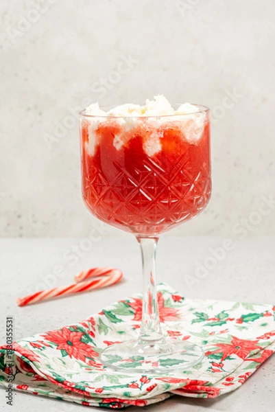 Fototapeta Refreshing holiday drink served in a crystal glass with whipped cream and candy cane on a festive napkin