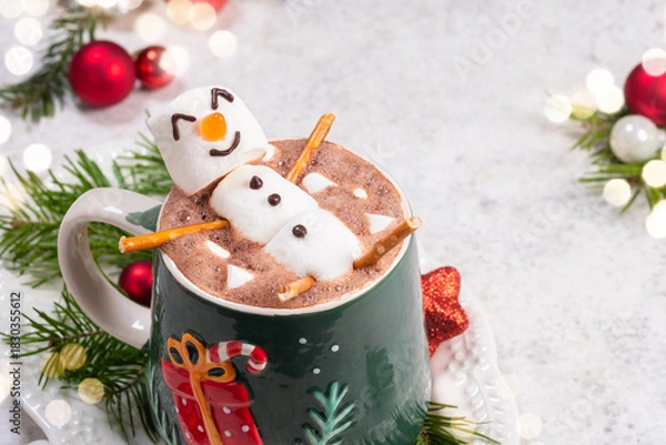 Fototapeta Cozy winter scene with festive hot chocolate topped by a playful snowman in a decorated mug