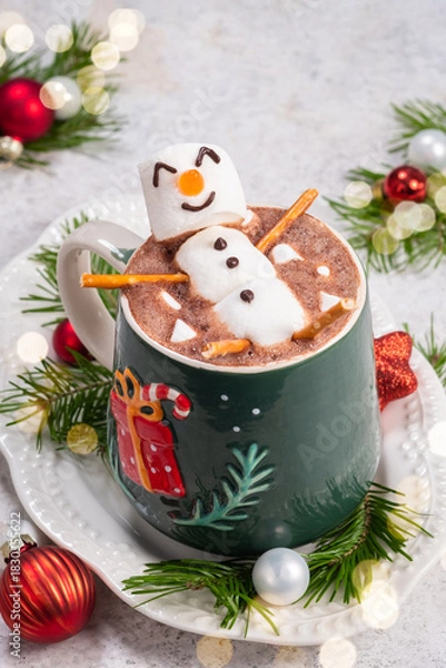 Fototapeta Cozy winter scene with festive hot chocolate topped by a playful snowman in a decorated mug