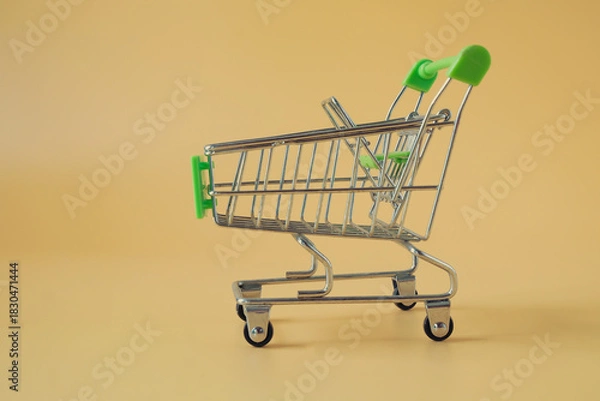 Obraz An empty tiny shopping cart on color background.