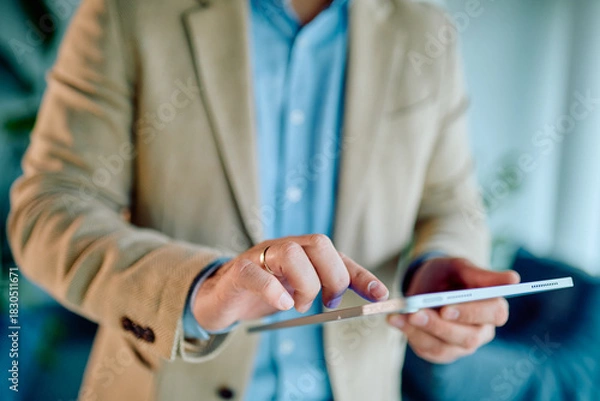 Fototapeta Businessman's hands holding and touching a touchscreen tablet, engaging with technology for business and lifestyle tasks