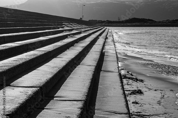 Fototapeta Concrete sea defence steps with strong shadows in black and white