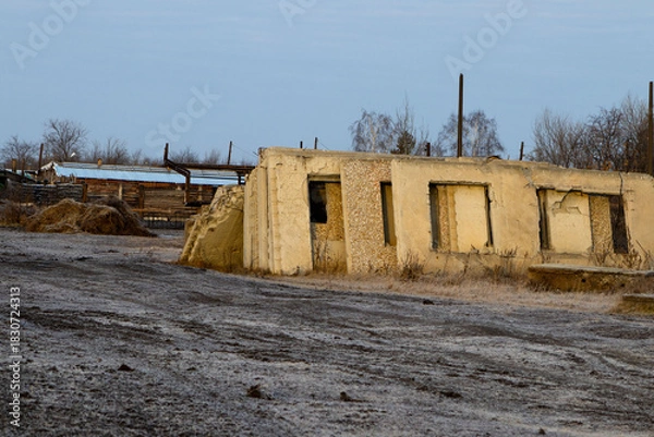 Fototapeta Abandoned, Earth-Toned Concrete Structure with Boarded-Up Windows and Frosted Ground