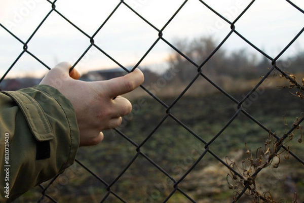 Fototapeta Hand Reaching Through Diamond-Patterned Chain-Link Fence