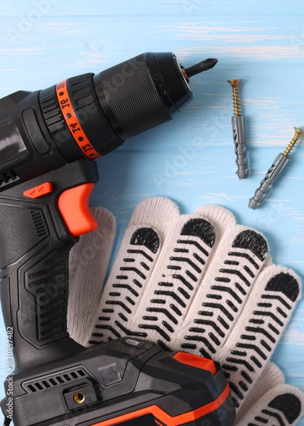 Obraz Vertical photo format. Cordless Drill Featuring Various Drill Bits Set Against a Vibrant Blue Background