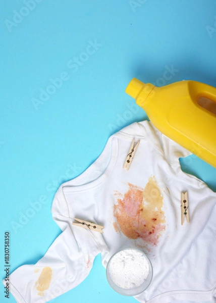 Obraz Vertical photo format.A Stained Baby Shirt, Resting with Detergent on a Bright Background Surface