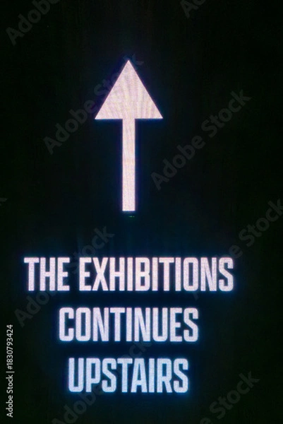 Obraz Stockholm, Sweden  A sign and an arow on a wall says the Exhibitions Continues Upstairs.