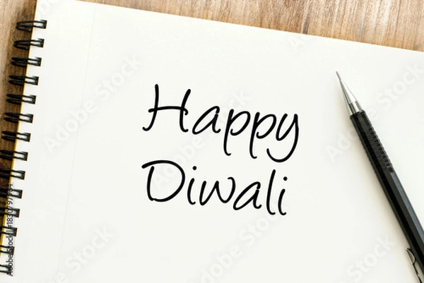 Obraz Heartfelt Happy Diwali message handwritten on a spiral notebook with a pen on a wooden background, symbolizing festive greetings and joyful celebrations