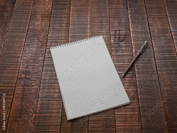 Fototapeta Notepad with a pen on a wooden table.