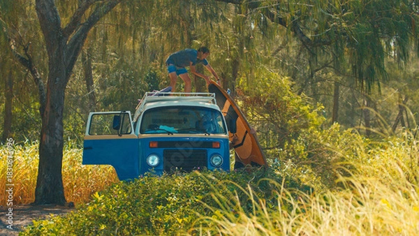 Obraz Two men unload surfing boards from the roof of the classic retro bus. Modern hippies travel by retro bus in a search of perfect waves in Brazil