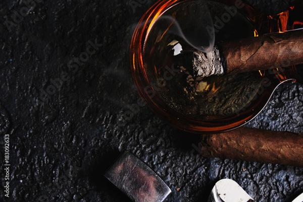 Fototapeta Glass of whiskey with smoking cigar and ice cubes on wooden table