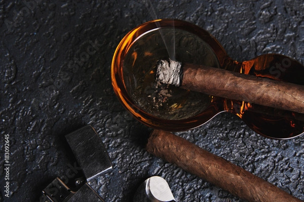 Fototapeta Glass of whiskey with smoking cigar and ice cubes on wooden table