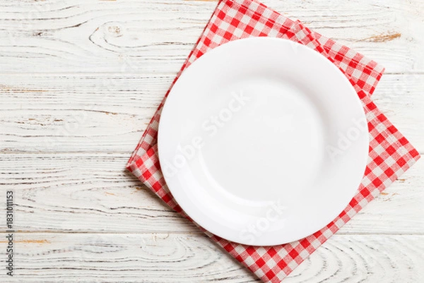 Fototapeta Top view on colored background empty round white plate on tablecloth for food. Empty dish on napkin with space for your design
