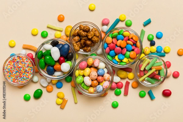 Obraz different colored round candy in bowl and jars. Top view of large variety sweets and candies with copy space