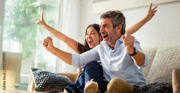 Obraz Excited couple celebrating during a sports game on TV at home