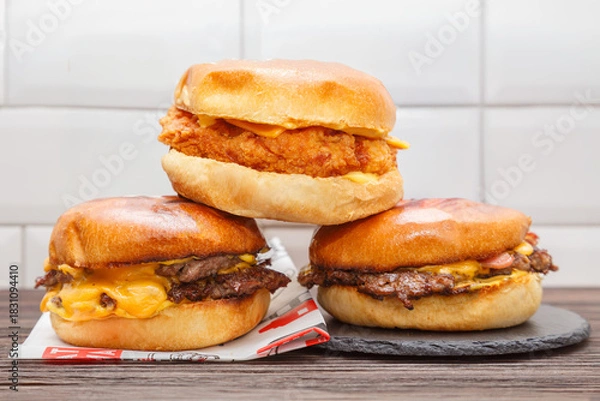Fototapeta Trois smash burgers sur ardoise (smash bacon, smash chicken et double smash), gros plan. Concept fast food. 