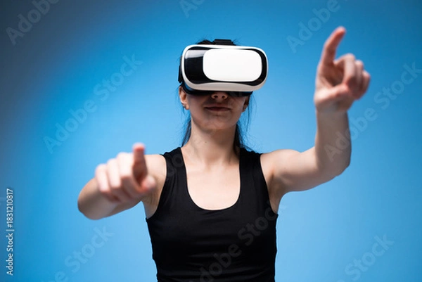 Fototapeta Woman using VR headset with extended arms while exploring dynamic virtual interface interaction