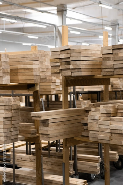 Fototapeta Stacked lumber fills a warehouse, neatly organized on pallets. Concept of resourcefulness, sustainable forestry, or raw materials for construction.
