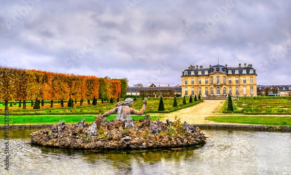 Fototapeta The Bassin de Scylla fountain in the foreground of the Chateau de Champs-sur-Marne near Paris. The historic French castle and formal gardens are seen under a cloudy sky