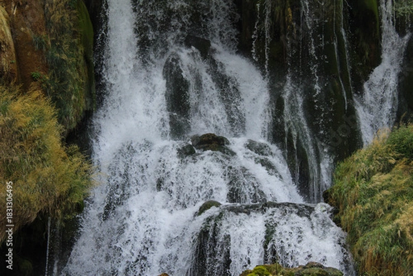Obraz Editorial photo of the Kravice Waterfall in Herzegovina, captured on August 24, 2025, showing powerful cascading water over mossy rocks.