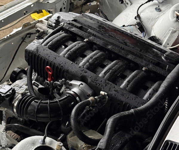 Obraz Engine parts are dampened by rain in a workshop setting, highlighting mechanical details