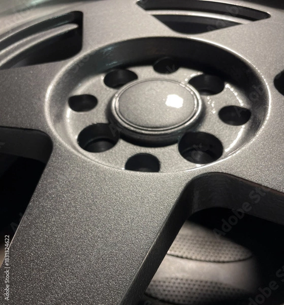 Obraz Close-up of a textured car wheel in a workshop, illuminated by daylight