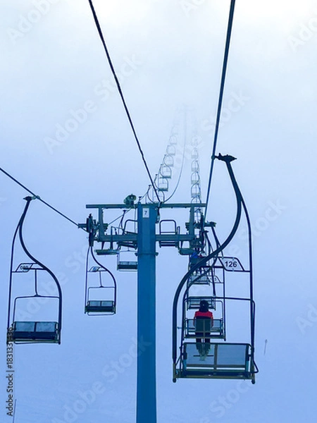 Obraz Chairlifts rise through thick winter fog on Jahorina Mountain, creating a serene alpine scene perfect for winter sports and travel concepts.