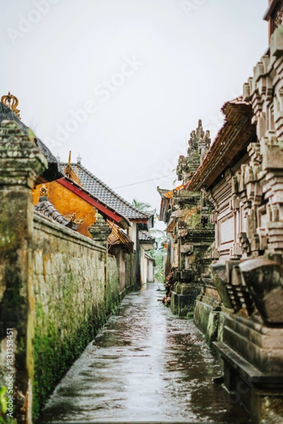 Fototapeta Narrow, wet Balinese alleyway with traditional stone architecture